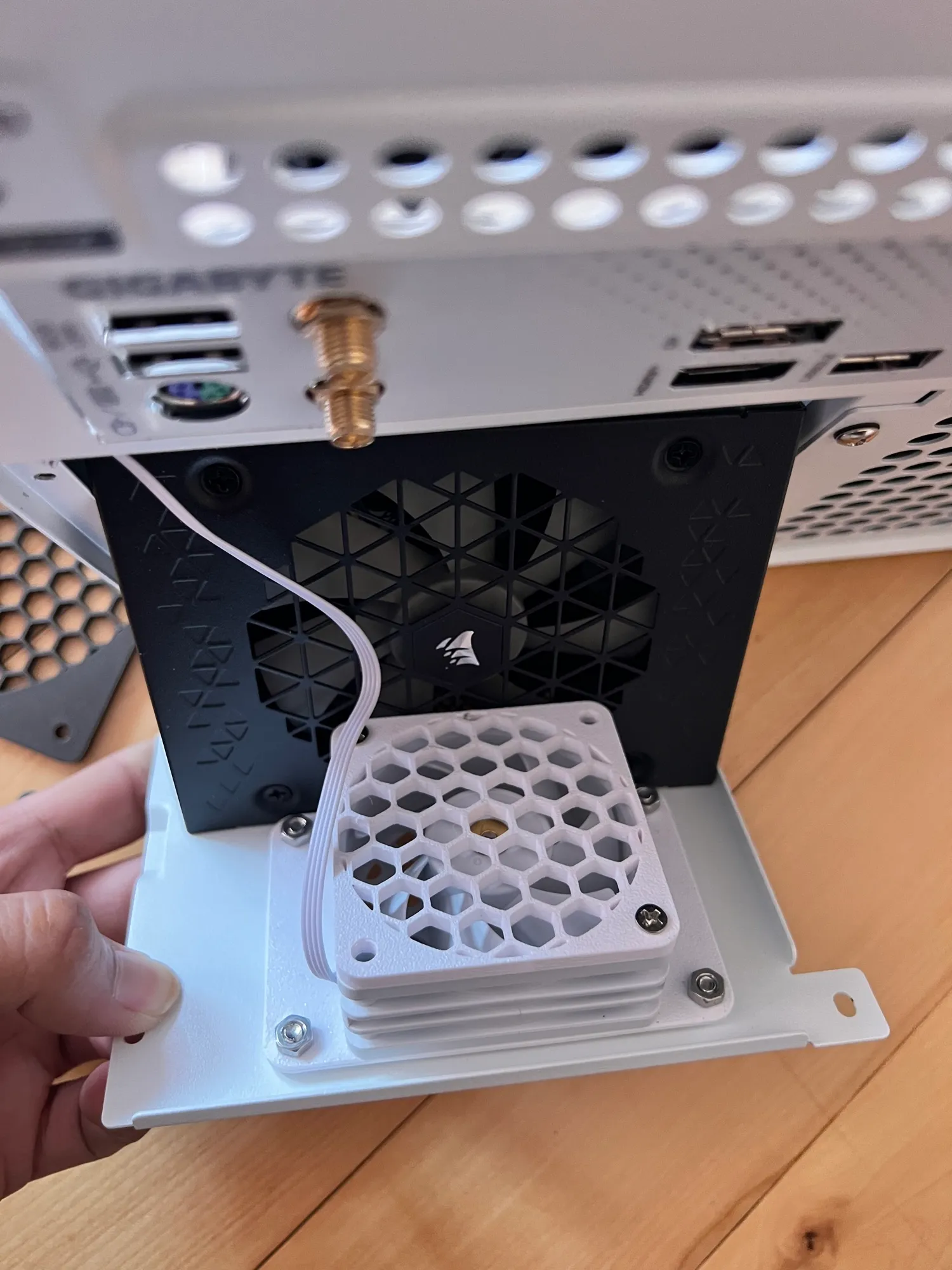 A small supplemental fan on the PSU bracket, behind a printed honeycomb guard